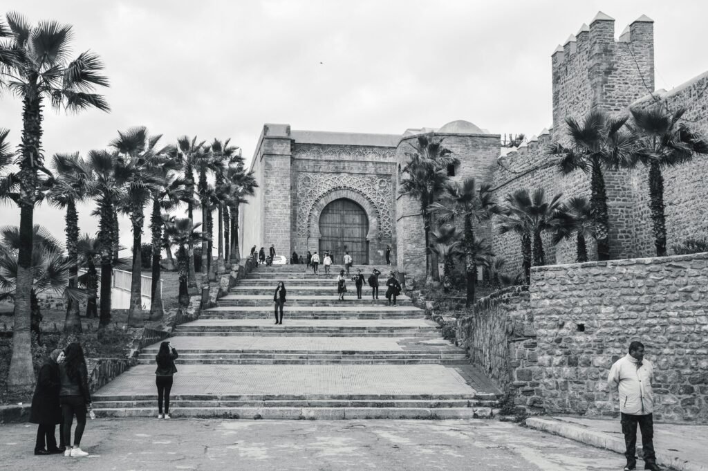 Monochrome view of the Kasbah of the Udayas entrance in Rabat, Morocco with people on steps.