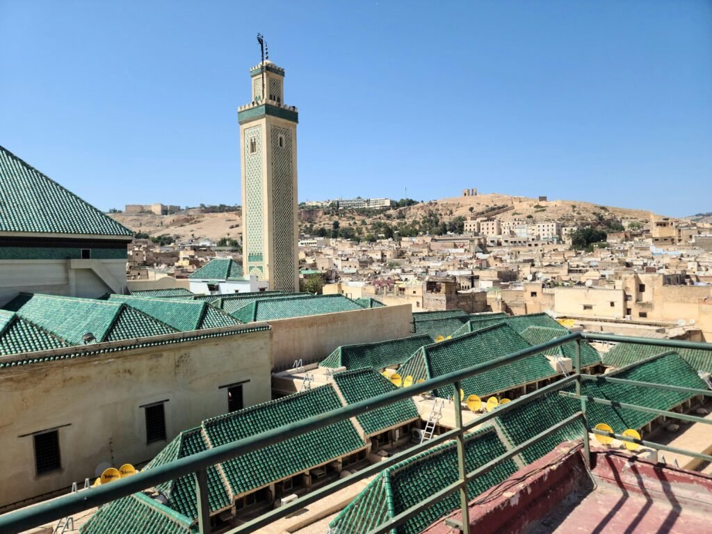 Aerial view of Fes with Kairaouine Mosque minaret under a clear blue sky.