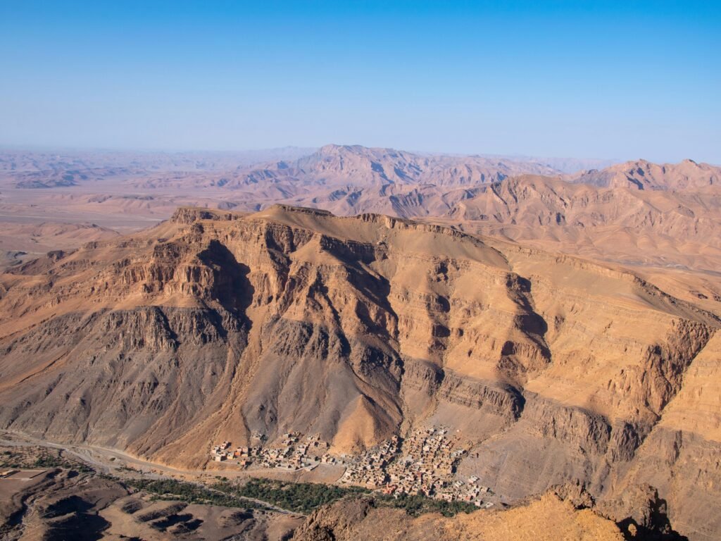 A breathtaking aerial view of the desert and rocky formations near Tata, Morocco under a blue sky.